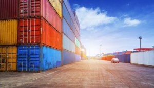 Empty road and containers in harbor at sunset