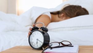 A young woman putting her alarm clock off in the morning