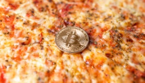 eine bitcoin münze auf einer pizza margaritha