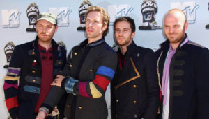 Die Bandmitglieder von Coldplay stehen vor einer Plakatwand für Fotoshooting.