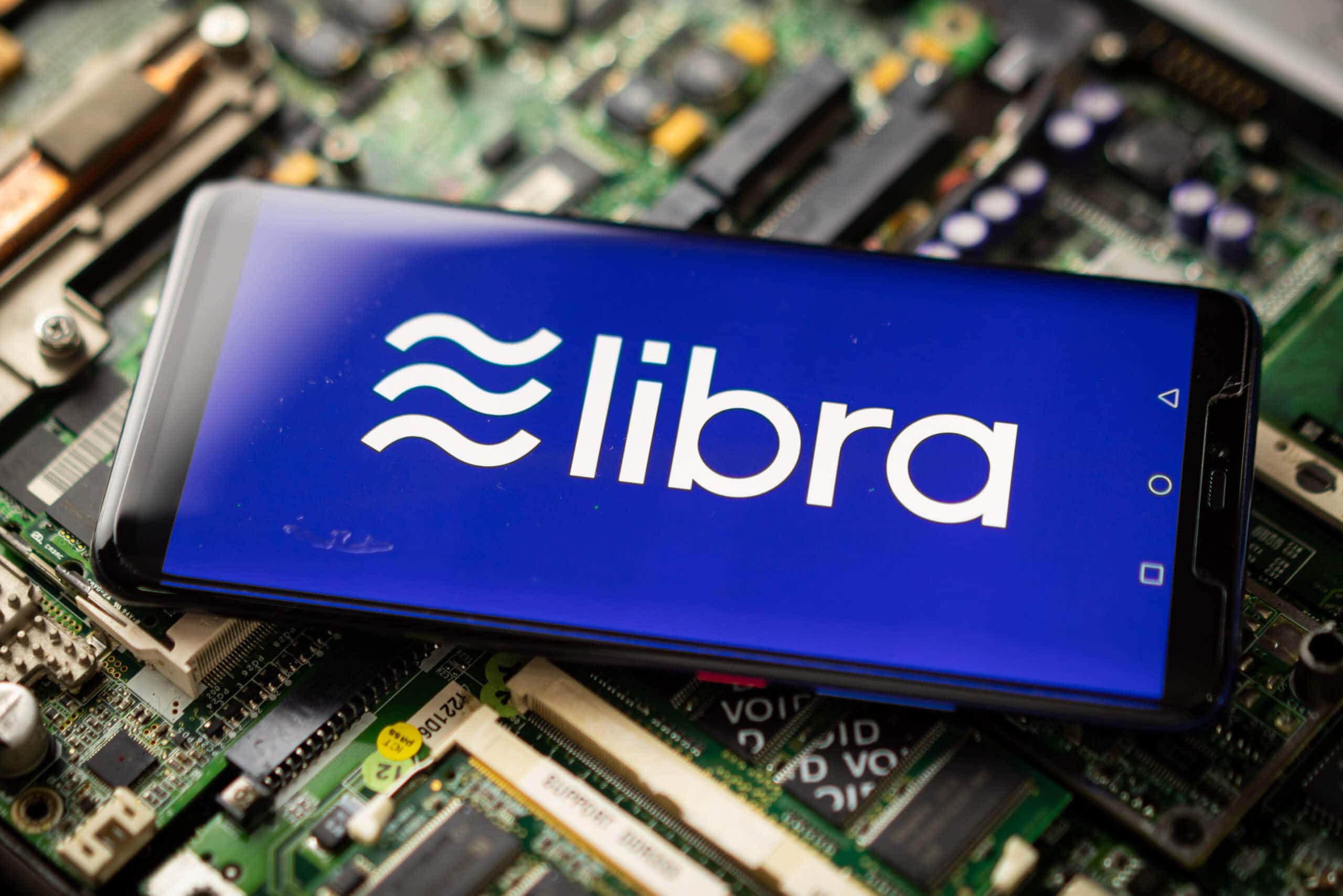 das libra-symbol auf einem smartphone, das auf einem elektronischen technologie-hintergrund liegt