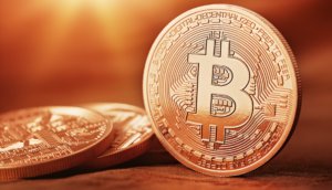 bitcoin-münze-steht-neben-liegenden-bitcoin-münzen