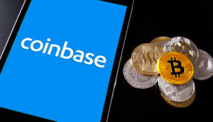 Smartphone mit Coinbase-Logo neben einem Stapel (Krypto-)Münzen
