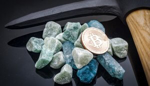 Steine und Bitcoin-Münze neben Spitzhacke
