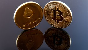 Ethereum-Münze und Bitcoin-Münze auf spiegelndem Untergrund.