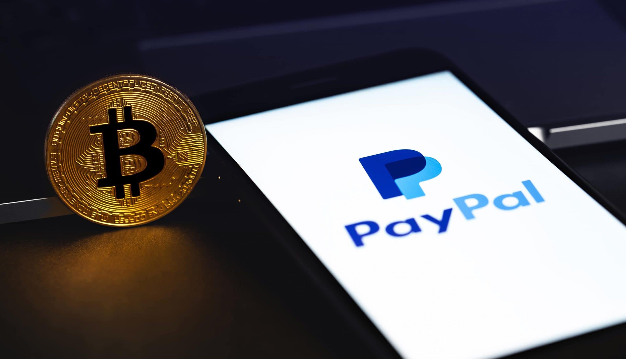 Bitcoin-Münze neben Smartphone mit PayPal-Logo