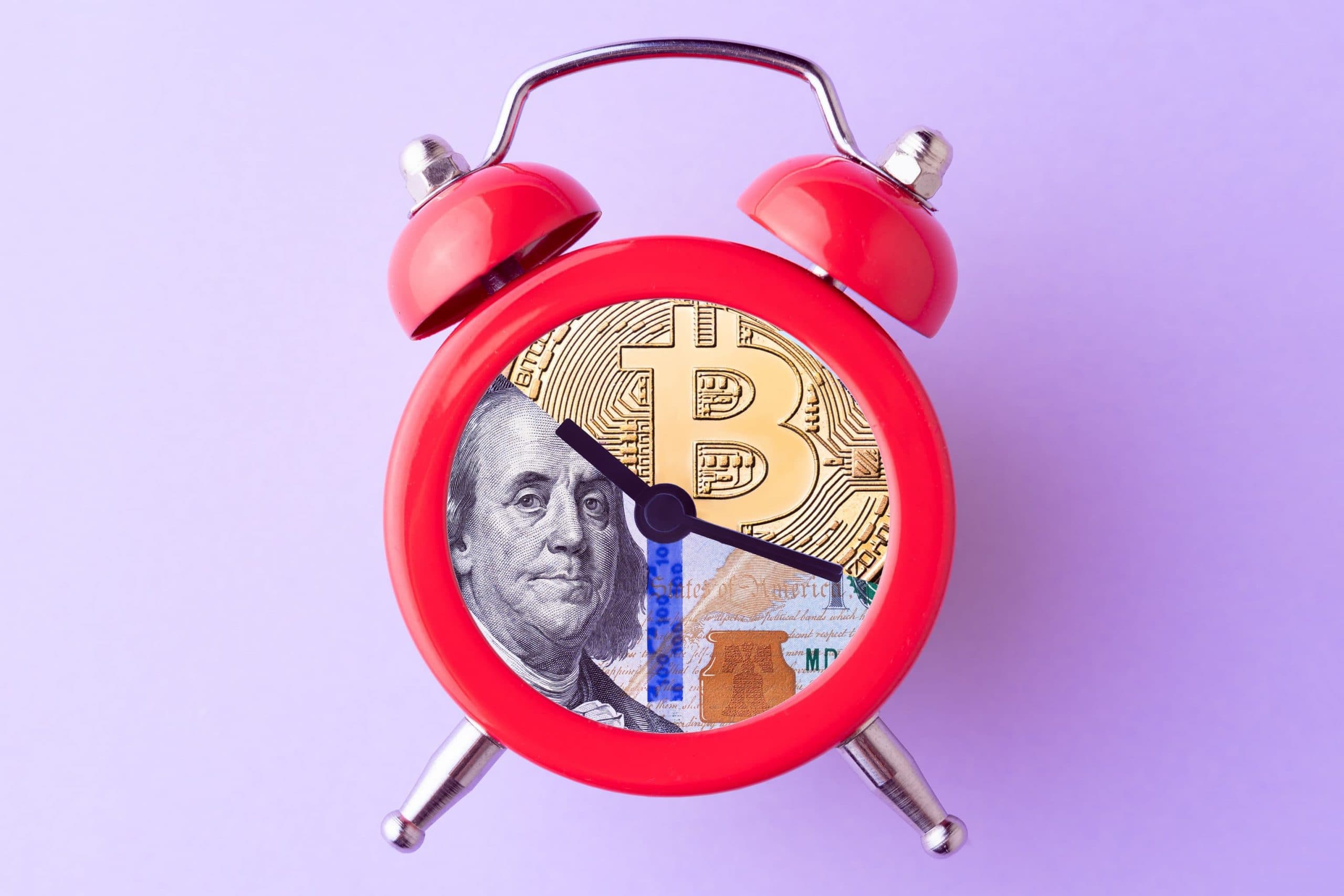 Roter Wecke, das Ziffernblatt bildet eine Collage aus Bitcoin und US-Dollar Fotos
