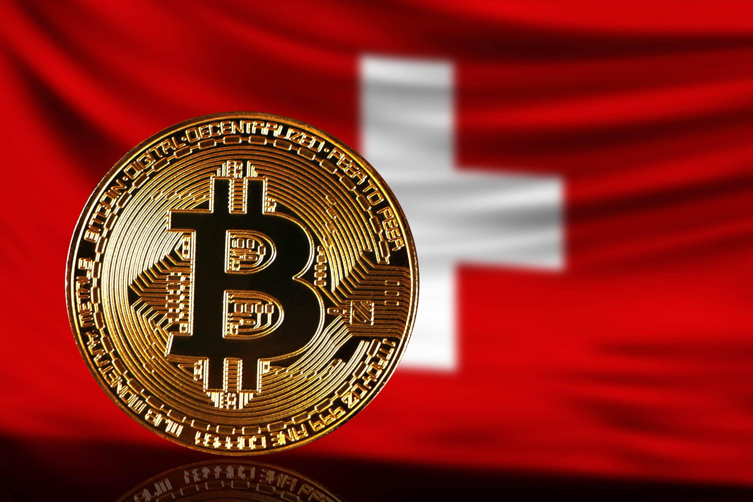 Eine Bitcoin-Münze vor einer Flagge der Schweiz (Bitcoin-ETP).