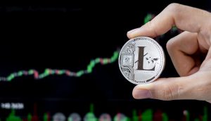 Litecoin-Münze wird vor einem Chart gehalten