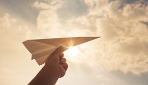 Hand hält Papierflieger