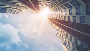 Aufnahme von futuristischen Hochhäusern. Am Himmel scheint die Sonne.