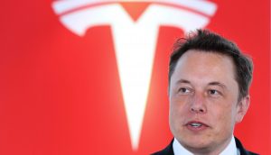 Elon Musk vor rotem Tesla-Logo