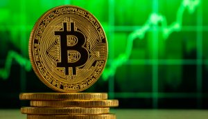 Eine Bitcoin-Münze vor einem grünen Chart. Bitcoin notiert im Plus.